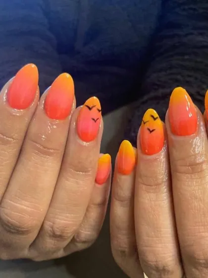 Get that sunset vibe with these beach-themed ombre nails. The colors blend from a warm orange to a bright yellow, with tiny birds hand-painted for a perfect vacation look.
