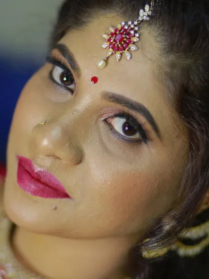 A close-up portrait of a bride with striking eye makeup and a ruby-adorned maang tikka.