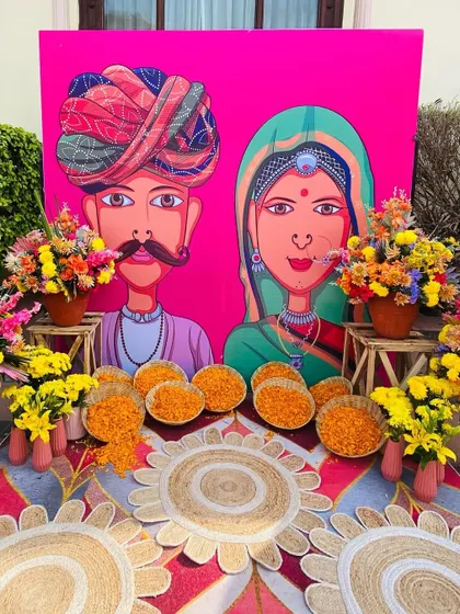 A close-up of our quirky Mehendi decor, featuring a bright pink backdrop with folk art and colorful flowers.
