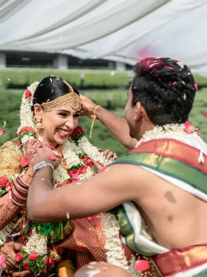 The groom places the sacred thread on the bride as she is held aloft by her family. This dynamic and joyous shot is a key moment in many South Indian weddings.