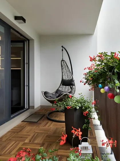 This clean and simple balcony design features a sleek black swing chair as the main focal point. Potted flowers and colorful baubles on the railing add a personal and cheerful touch.