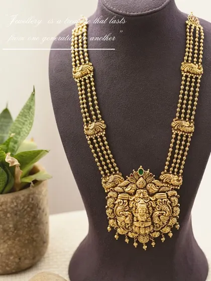 Product styling for a traditional temple jewelry necklace from Manjali Jewellers. The piece is displayed on a bust form against a simple background, allowing the intricate craftsmanship of the pendant to be the sole focus.