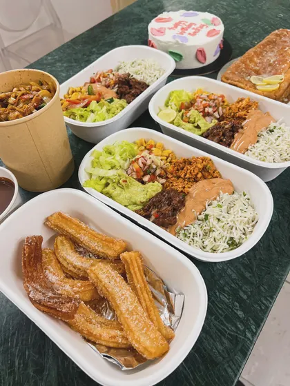 A large order of Mexican rice bowls, churros, and a custom cake ready to be delivered. This shows a typical mix of savory and sweet items my clients love.