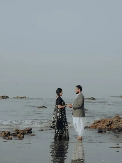 A simple, elegant pose on a rocky beach, with the couple holding hands against the serene ocean backdrop.