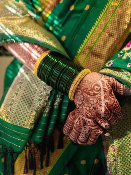 The traditional 'Hirva Chuda' or green bangles, an essential part of a Marathi bride's attire. Paired with her henna-stained hands, it's a beautiful symbol of her new journey.