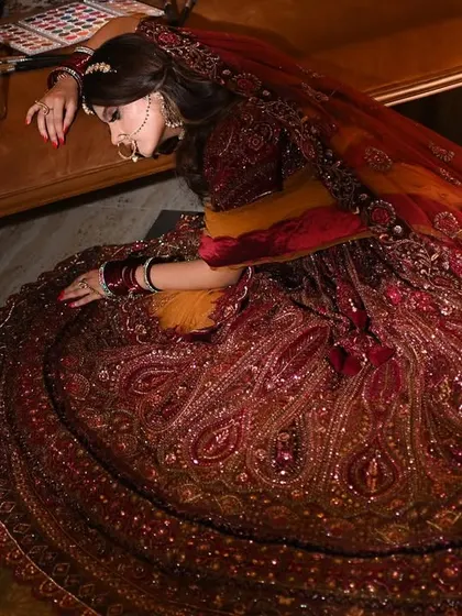 A dramatic, high-angle shot focusing on the rich texture and design of the bridal lehenga.
