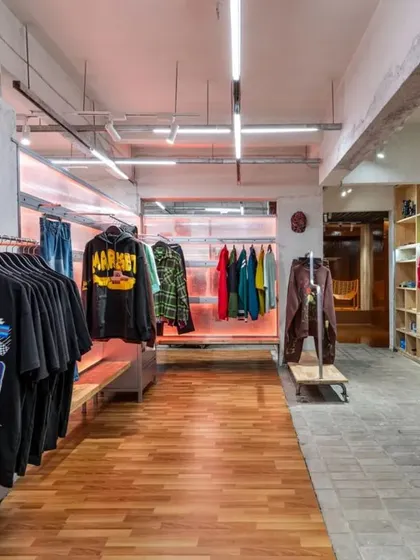 A view of the main retail floor, showing the contrast between the warm wooden flooring and the industrial concrete pavers. The movable clothing racks and displays allow for complete flexibility.