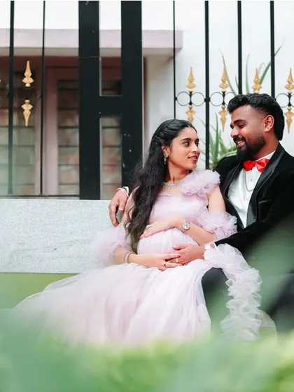 A serene moment on a park bench. The soft pink of the gown stands out beautifully against the greenery, making for a picture-perfect maternity photo.