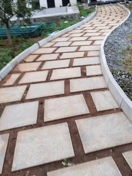 A winding pathway made from stone pavers with a raised concrete edge, guiding movement through the garden. The gentle curve adds visual interest and softens the lines of the landscape.