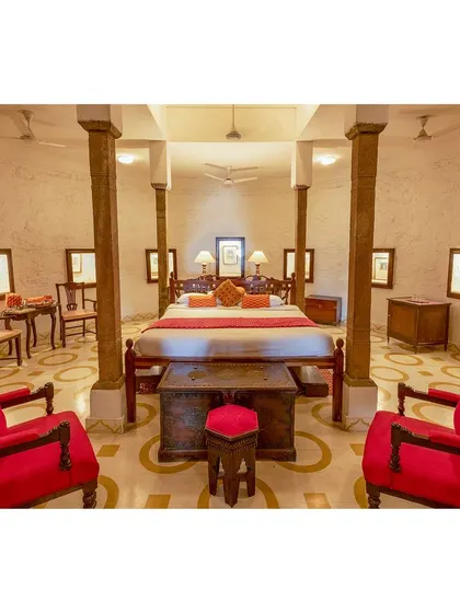 A symmetrical composition of a hotel suite, where the bold red chairs anchor the frame. This image highlights the spaciousness and regal design of the room.