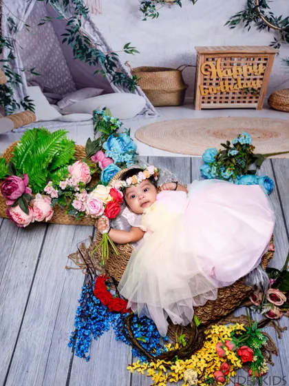 A lovely infant portrait in a basket of colorful flowers. The overhead angle and the baby's sweet expression make this a beautiful and artistic shot.