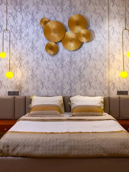This bedroom makes a statement with a textured wallpaper, unique gold wall art, and hanging pendant lights. The design is bold and artistic, creating a sophisticated and personalized space.