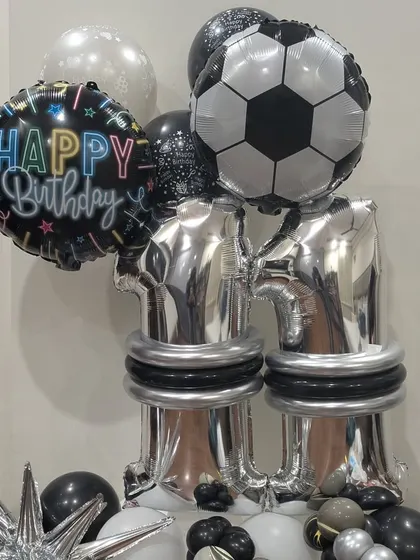 A close-up of the football balloon arrangement, showing the "Happy Birthday" foil balloon and chrome silver details.