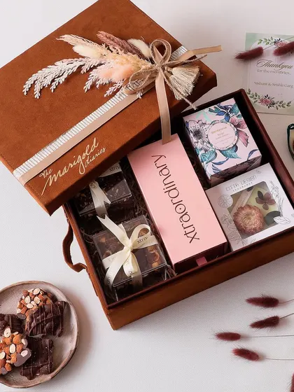 Unwrapping the magic of Diwali with this hamper, which includes a wax tablet, tin candle, hazelnut cookies, nutty barks, and clusters.