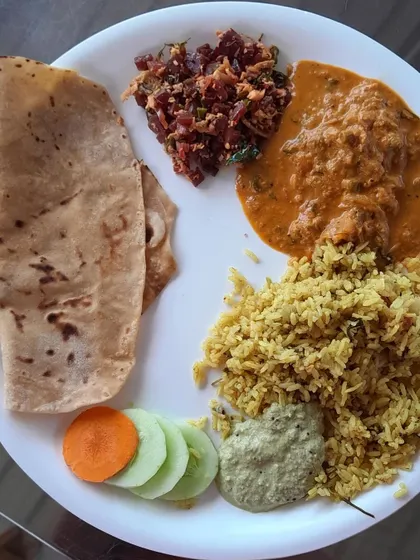 A plated view of what a typical meal looks like. This plate has a chapati, vegetable pulao, a rich paneer gravy, beetroot palya, coconut chutney, and a fresh salad.