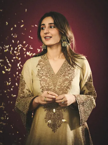 A moment of celebration. The falling petals add a magical, festive touch to this shot, highlighting the joy and spirit of the occasion. The embroidered kurta is both elegant and comfortable.