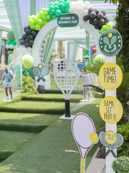 The entrance walkway designed to look like a path to a tennis court, complete with a net, racket props, and themed signs.