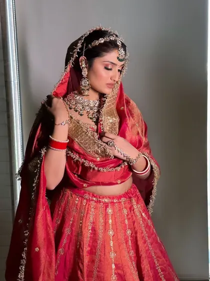 A full-length view of the red silk lehenga, highlighting its elegant fall and the intricate gold border.