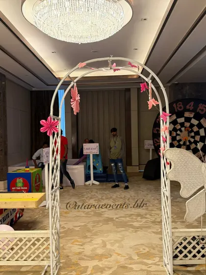 The party space includes a dedicated game zone, marked by a white arch decorated with butterflies, leading to activities like a dart board and "Hit the Frog".