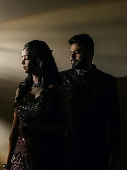 A moody and romantic portrait of the couple. The dramatic shafts of light cut through the darkness, creating an intimate and cinematic atmosphere.