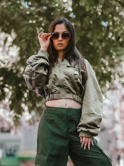 A medium shot focusing on the model's confident expression and pose. The sunglasses add to the cool, edgy look.