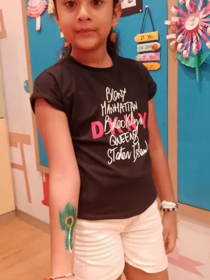 A guest shows off her peacock feather arm tattoo, a popular design during our Janmashtami celebrations. We can tailor our art to match party themes or holidays.
