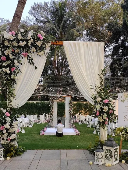 An elegant outdoor Christian wedding ceremony with a beautiful floral arch and white drapery.