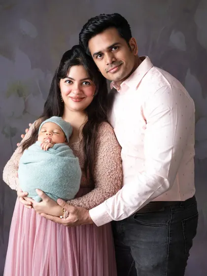 A beautiful family portrait against a soft, floral background, celebrating their new arrival.