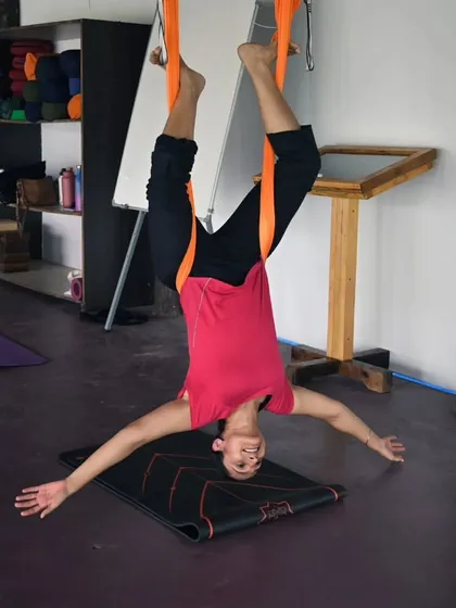 A student enjoying the feeling of a deep, supported stretch in the aerial hammock. These moments of release are what make the practice so powerful.