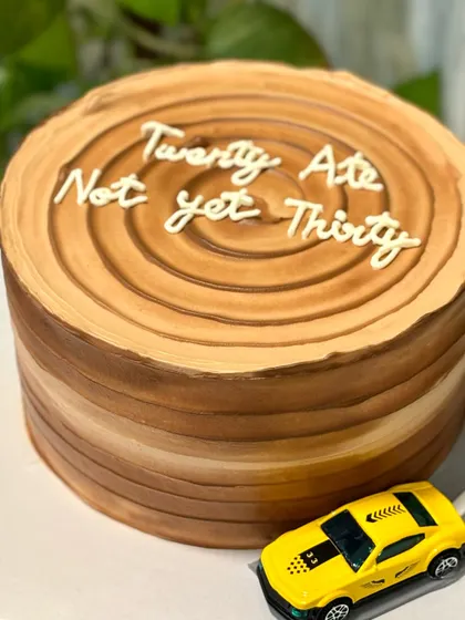 "Twenty Ate, Not yet Thirty." This witty 28th birthday cake is designed to look like a tree trunk, complete with a toy car driving on a fondant road.