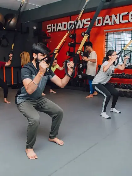 Members perform TRX squats, a functional exercise that builds leg strength and improves mobility. The studio is fully equipped to support a variety of suspension training workouts.