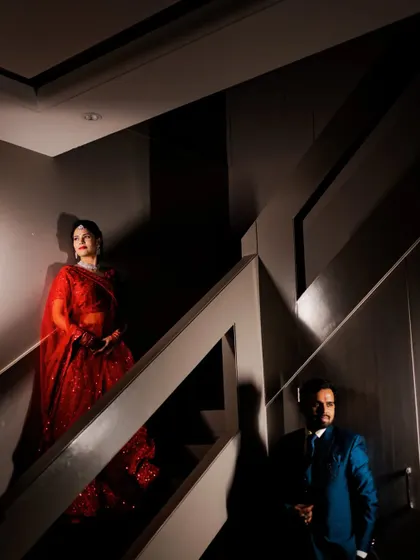 A dramatic, artistically lit portrait of Deepak and Deepa on a staircase during their Sangeet night. The play of light and shadow creates a moody and cinematic feel.