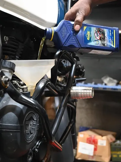 Pouring fresh Putoline oil into the Himalayan. Regular oil changes are the lifeblood of a healthy engine.