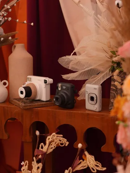 A collection of instant cameras is placed on a wooden console table, inviting guests to capture and share their memories.