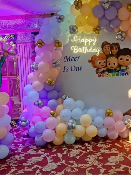 A sweet Cocomelon first birthday setup in pastel colors. This decor includes a custom circular backdrop, a light-up number '1', and a character cutout, perfect for a toddler's party.
