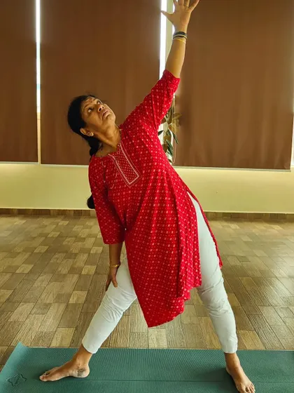 A student demonstrates Trikonasana (Triangle Pose). This foundational pose is excellent for stretching the sides of the body, hamstrings, and opening the hips.