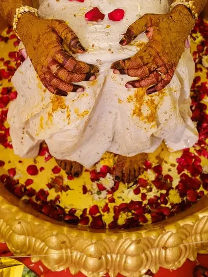 A close-up of the bride's hands and feet covered in turmeric and flower petals during the haldi ritual, capturing the textures and colours of the ceremony.
