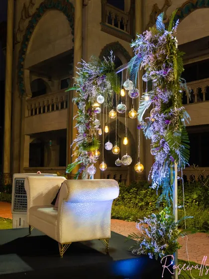 This photo shows a dedicated photo or seating spot for the couple, framed by lush floral pillars and hanging lights, creating a perfect picture opportunity.