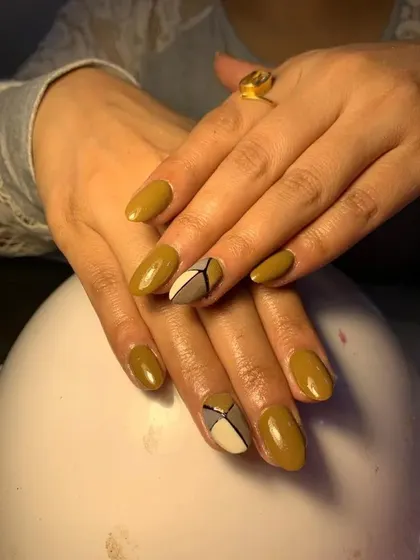 A sophisticated design with a mustard yellow base and geometric color-blocked accent nails.
