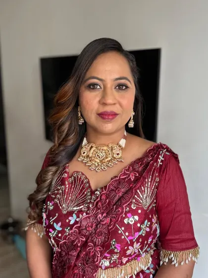 A beautiful client in a maroon embroidered saree. Her makeup is soft and warm, with a focus on her eyes.