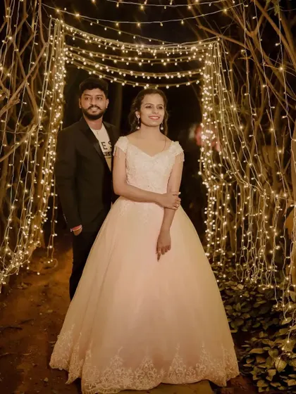 A couple stands in a tunnel of fairy lights. The classic silhouette of our pink ball gown shines in this magical setting.