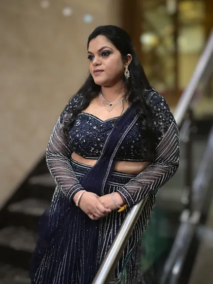 A glamorous look for a wedding event. The makeup features a classic smokey eye and a neutral lip, paired with a sparkling navy blue lehenga for a sophisticated and modern feel.