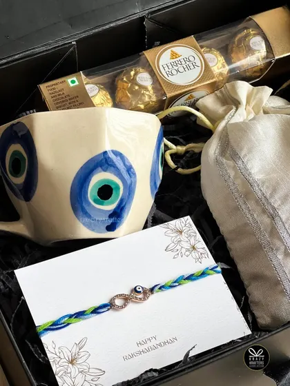 A close-up of the hand-painted evil eye mug and matching rakhi from our 'Raksha' hamper.