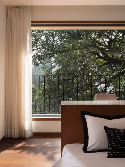 This detail shot from the son's bedroom shows how the bed is positioned to offer an immersive experience of living with nature. The view of the lush greenery is the primary focus of the room.