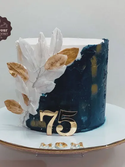 A sophisticated cake for a 75th birthday, featuring a deep blue and white textured design with wafer paper leaves. This gulab jamun flavored cake shows how traditional flavors can be presented in a contemporary style.