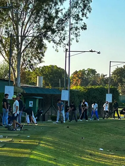 A packed driving range in the late afternoon sun, full of energy and activity.