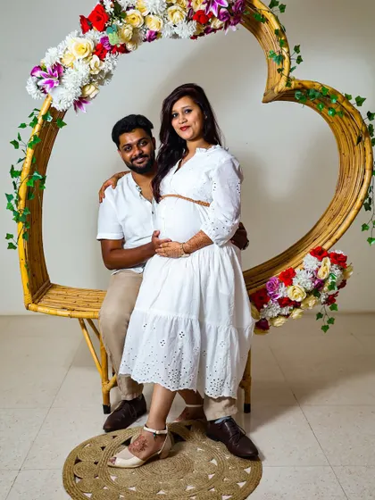 For a more modern and styled maternity shoot, I use props like this heart-shaped frame and a clean background. This shows a different style, focusing on the couple in a beautifully composed studio setting.