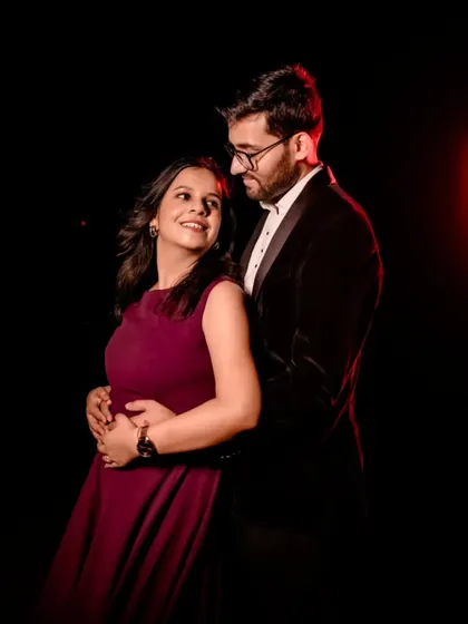 An intimate studio portrait with dramatic lighting. The bride's simple wine-colored gown and the groom's velvet tuxedo create a sophisticated and timeless look.