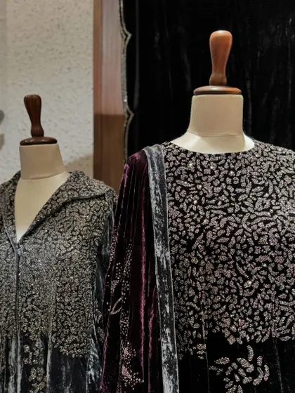 A close-up of the intricate silver embroidery covering the yoke of a charcoal grey velvet outfit.