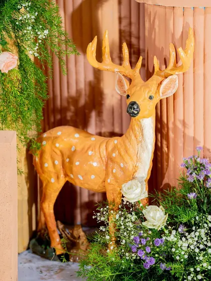 A life-like deer prop surrounded by flowers, a key element in our woodland and enchanted forest themes.